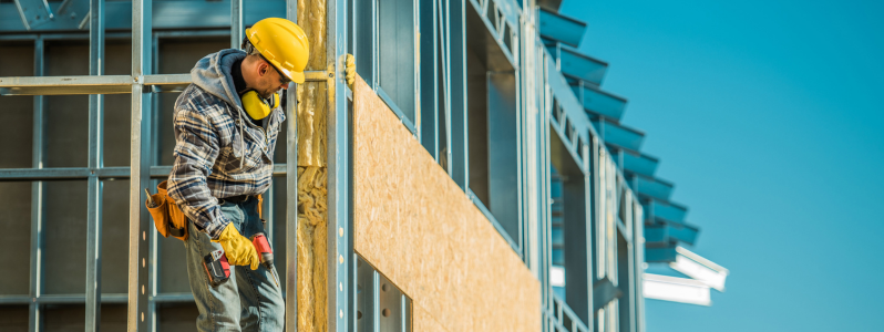 Profissional executando trabalho em altura NR-35 em estrutura metálica durante obra comercial