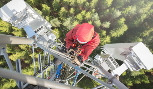 Técnico executando alpinismo industrial com acesso por corda em torre de telecomunicação conforme NR-35