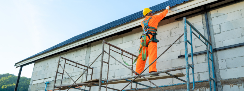 Trabalhador em andaime com cinto de segurança durante treinamento NR 35 para trabalho em altura.